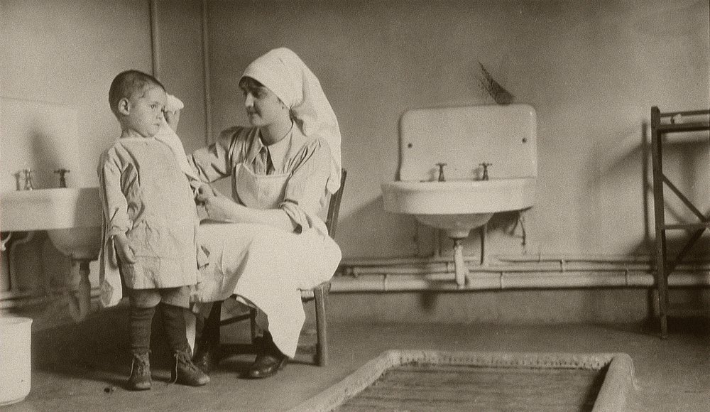 Nurse Tending a Sick Child at Passay and Saint-Quentin Colonies for Refugees and Orphans, 1919 by American Photographer