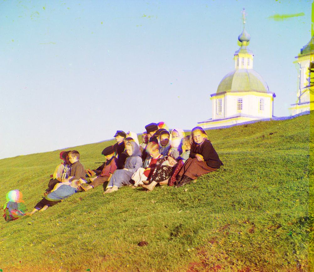 Russian children sitting on the side of a hill near a church and bell ...