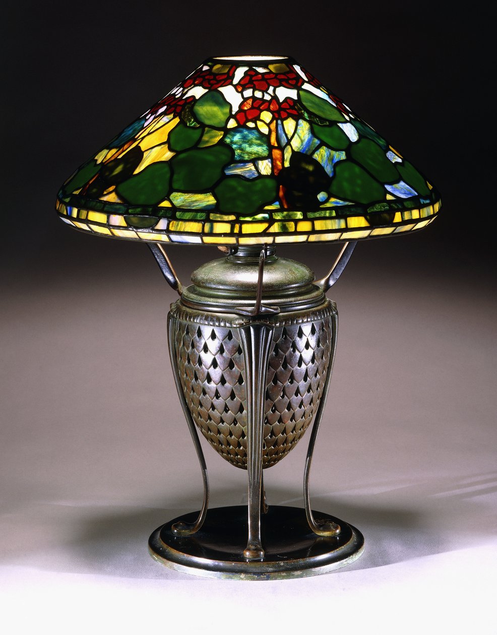 A "Geranium" table lamp with a conical shade, and reticulated bronze urn base with a fishscale pattern, 20th century by American School