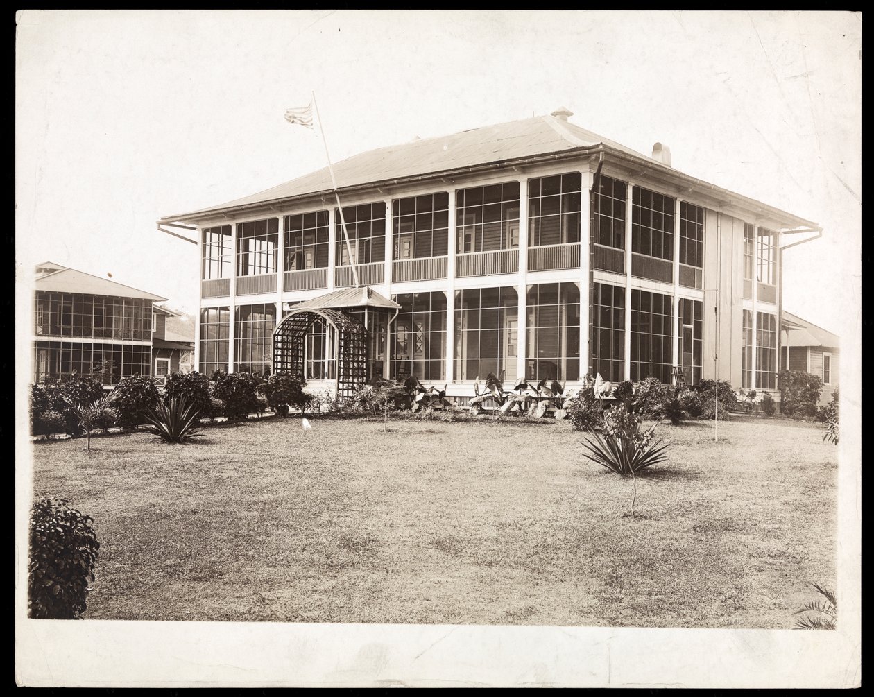 A Two-Story House Surrounded by Porches, with an American Flag Flying; in Panama During the Construction of the Canal by Byron Company