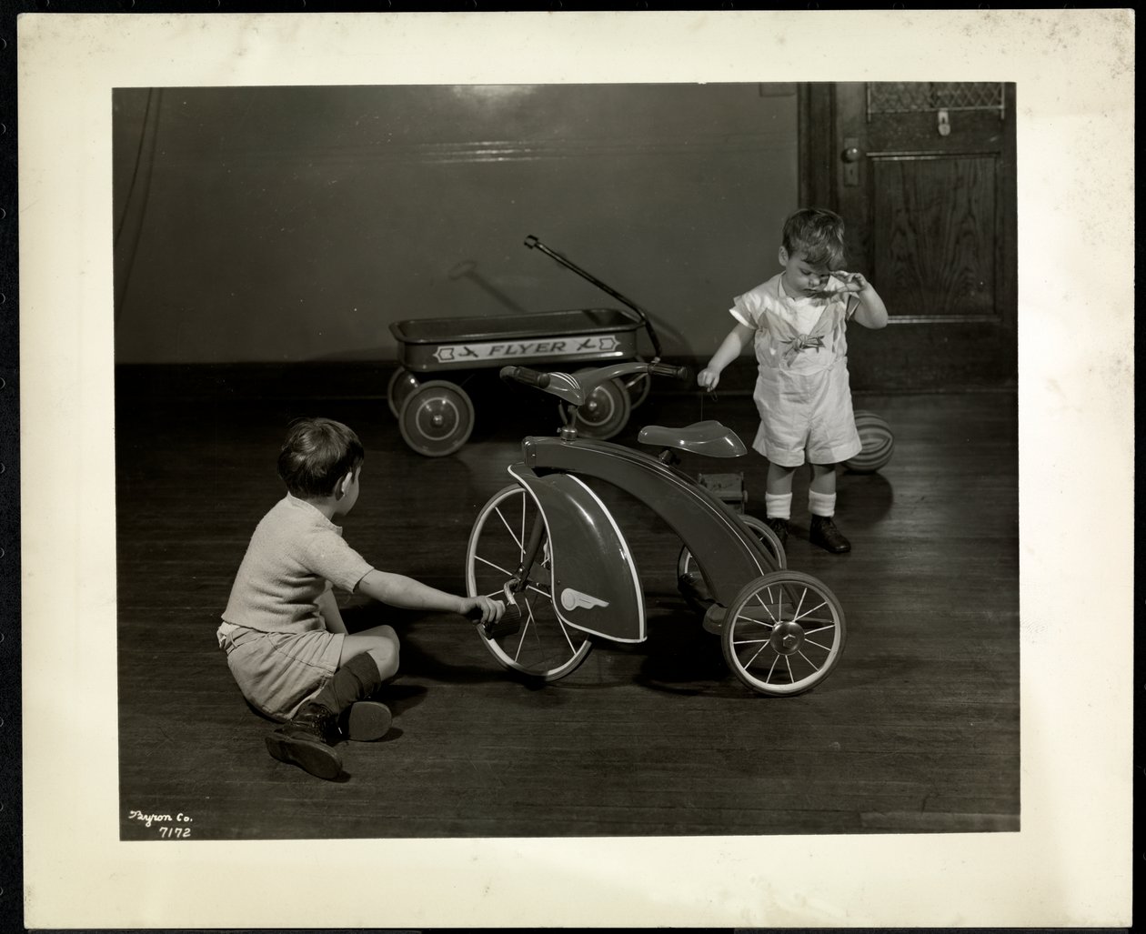 Two blind visually impaired boys playing with a tricycle and red wagon at the New York Association for the Blind, 111 East 59th Street, New York, 1937 by Byron Company
