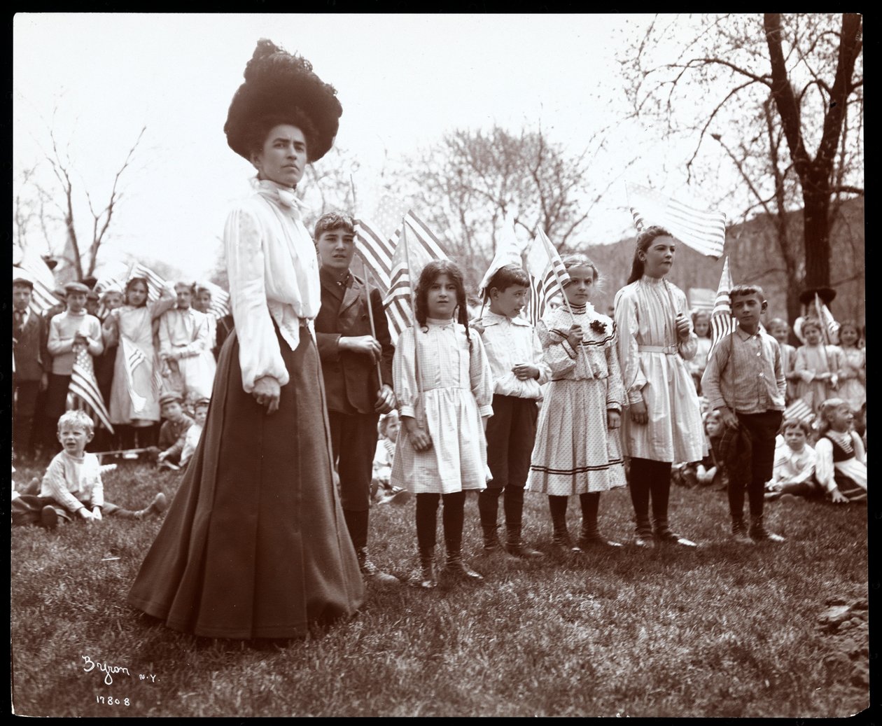 Woman with children holding flags on Arbor Day at Tompkins Square Park, New York, 1904 by Byron Company