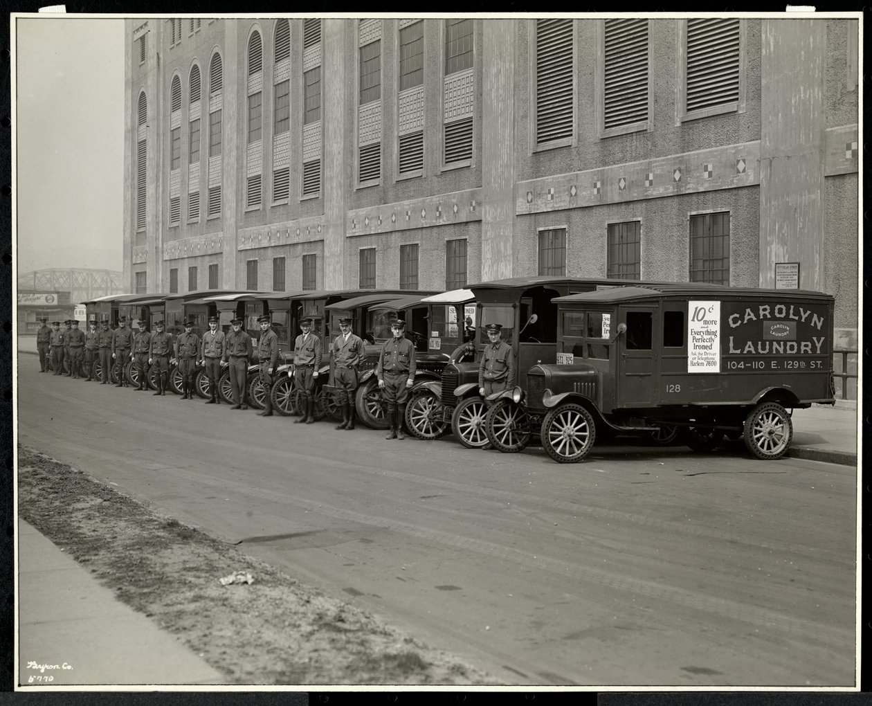 A line of delivery trucks parked outside the Carolyn Laundry at 111 East 128th Street, East Harlem, New York, 1929 by Byron Company