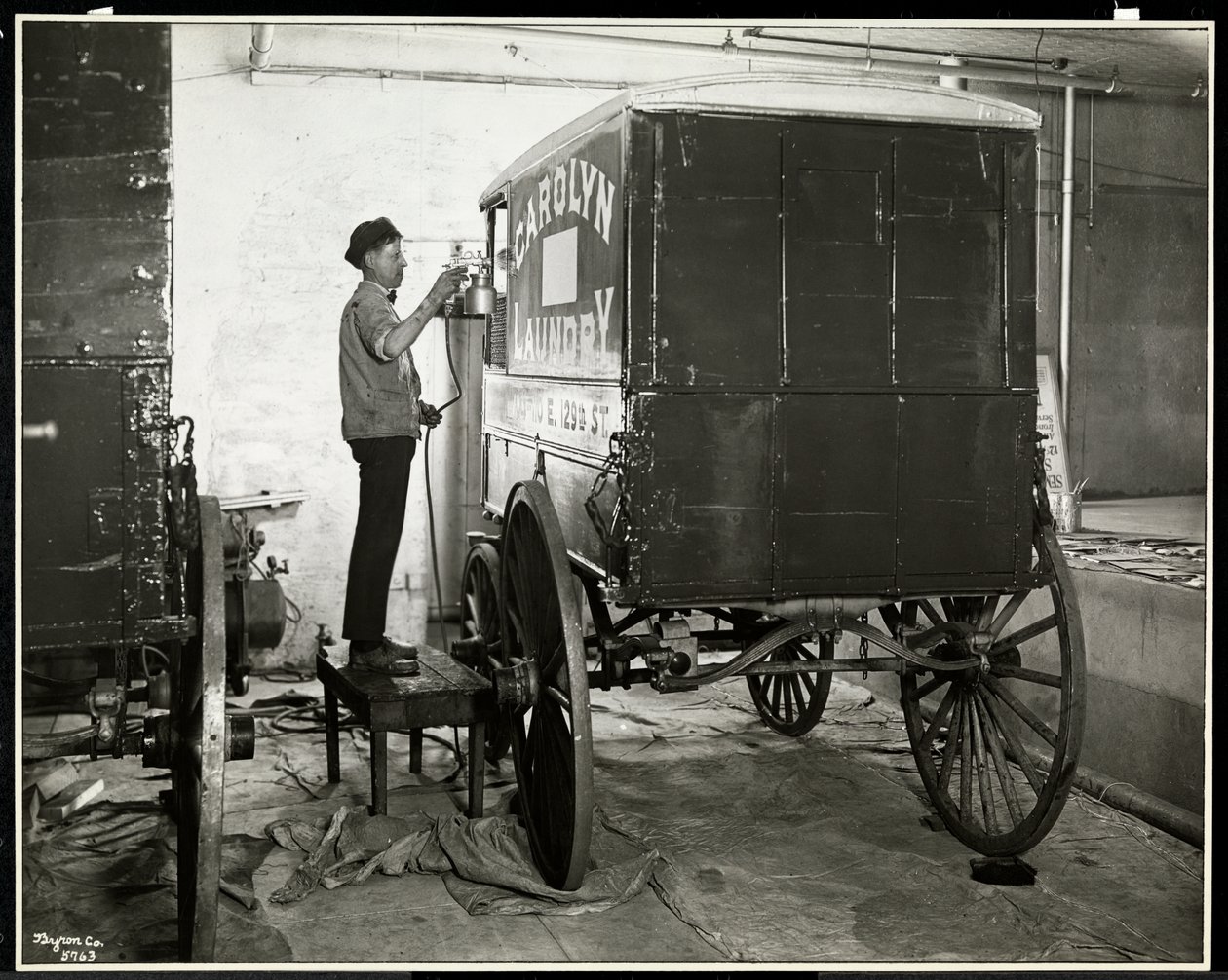 A Man Spraypainting a Delivery Wagon of the Carolyn Laundry at 111 East 128th Street, East Harlem, New York, 1929 by Byron Company