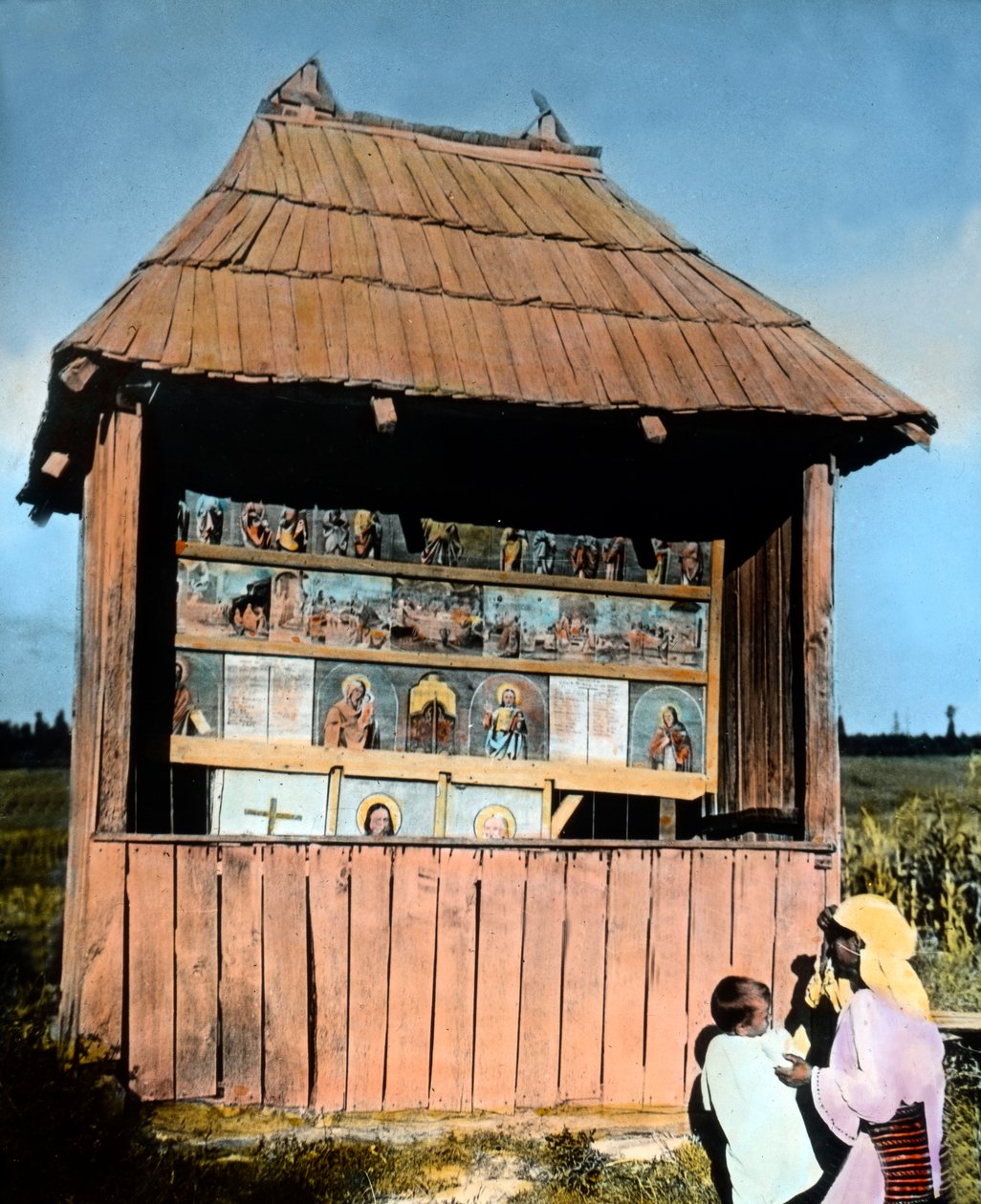 Mother with child in front of a little chapel with pictures of the Saints, Bukovina, Romania, circa 1920 by Carl Simon
