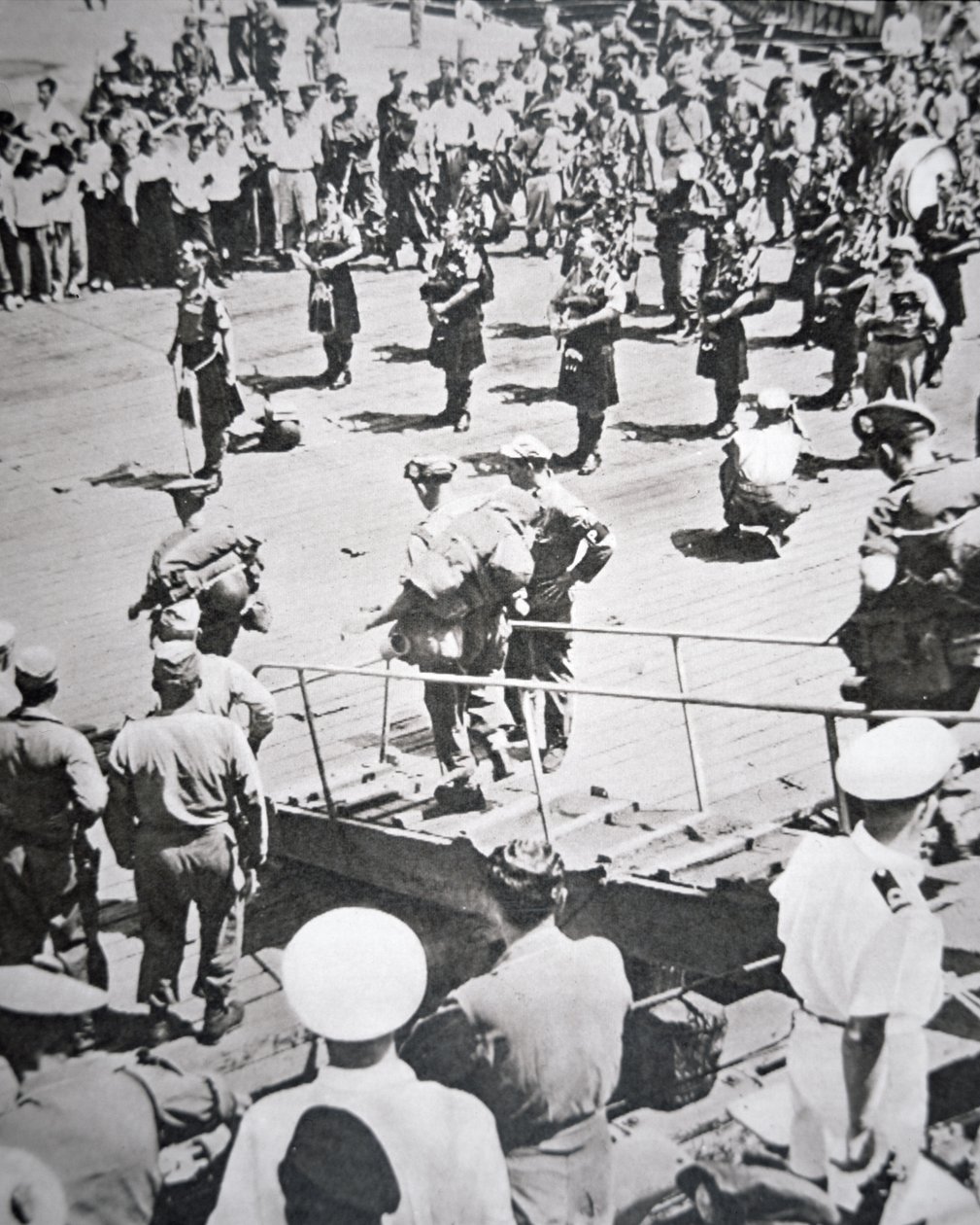 Kilted pipers play ashore from the 1st Battalion Argyll and Sutherland Highlanders from HMS Ceylon at Pusan, 29th August 1950 by English Photographer