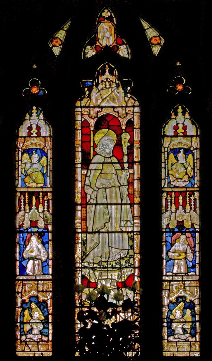 The East window depicting musician angels surrounding the central figure of a sainted bishop by English School