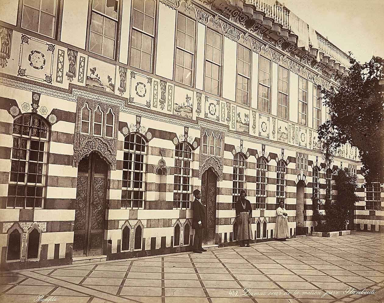 The courtyard of a Jewish house in Stambouli, Syria, Three domestics are shown near the walls of the building by Félix Bonfils