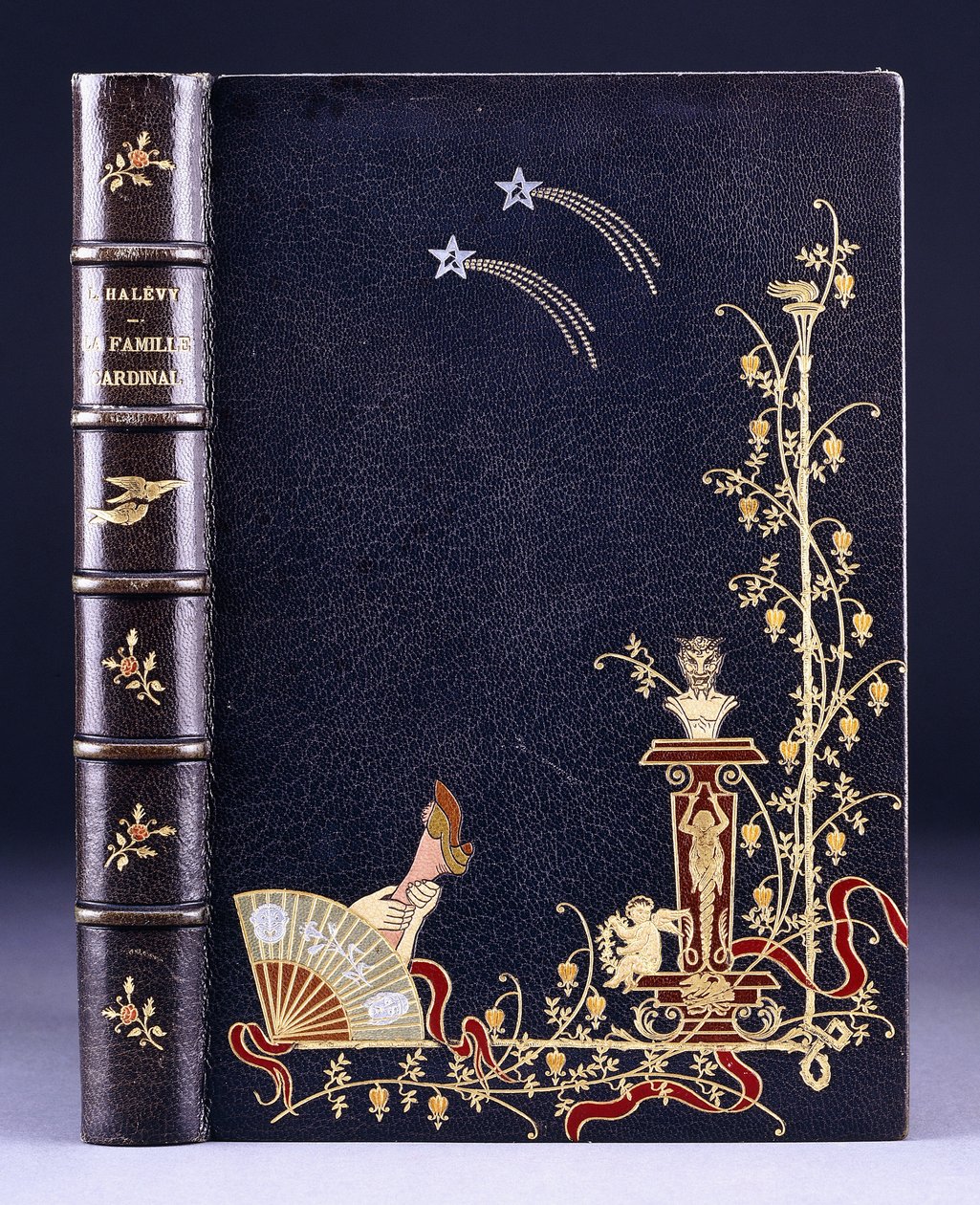 Upper book cover of two shooting-stars, a torch, foliage, faun on pedestal, putto and a leg behind a fan, 1893 by French School