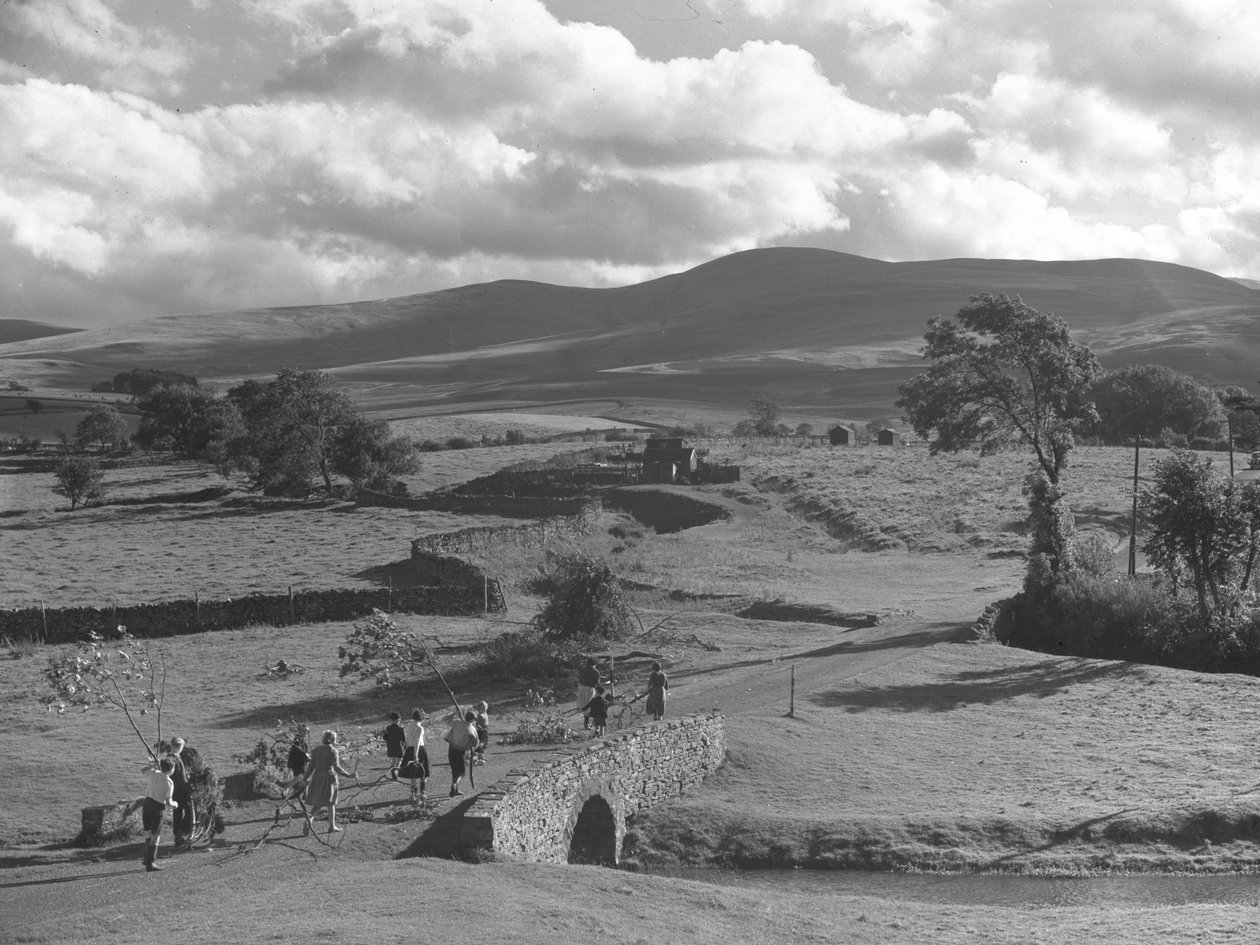 Children and adults carrying tree branches over a bridge, possibly for a bonfire by Joseph Hardman