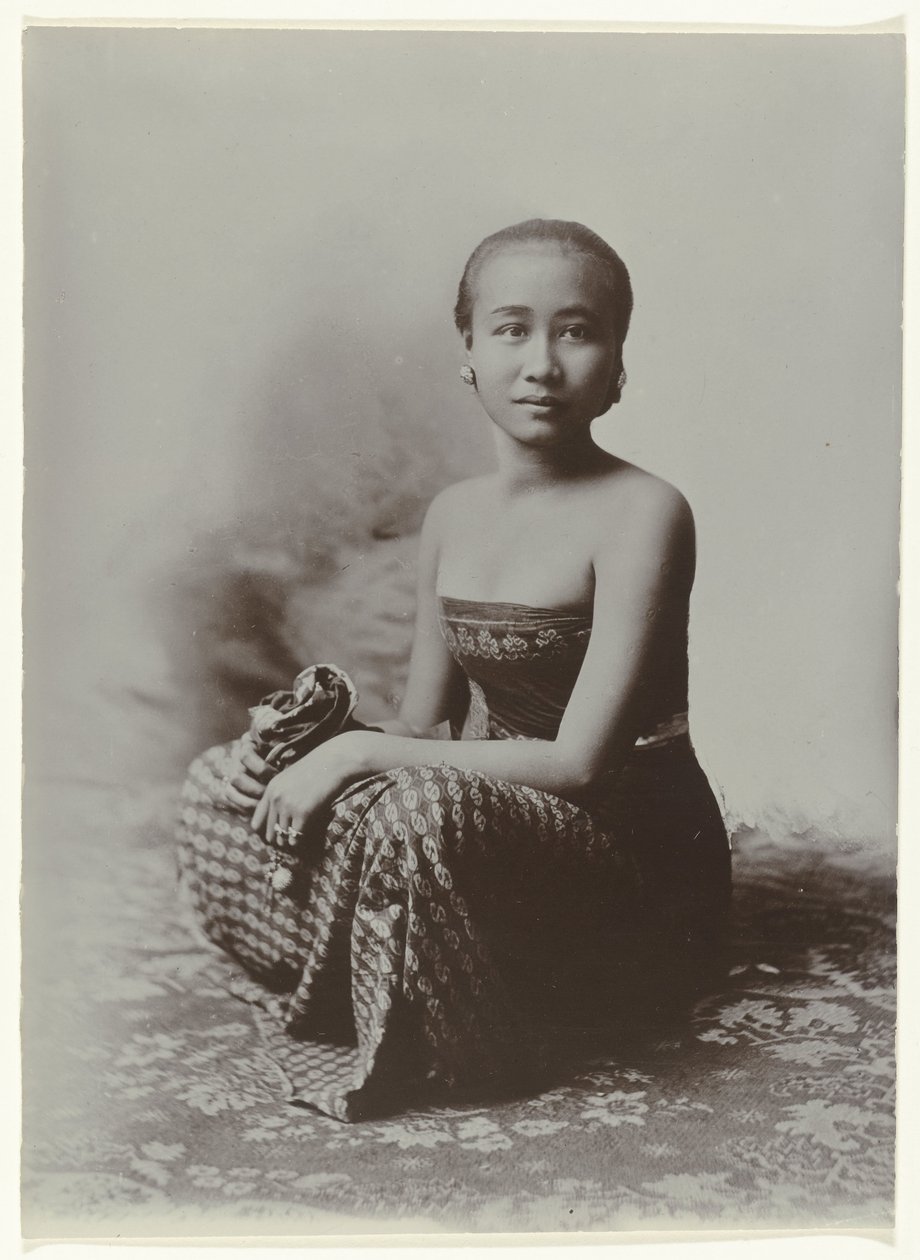 Studio portrait of a seated young Javanese woman in a sarong with batik ...