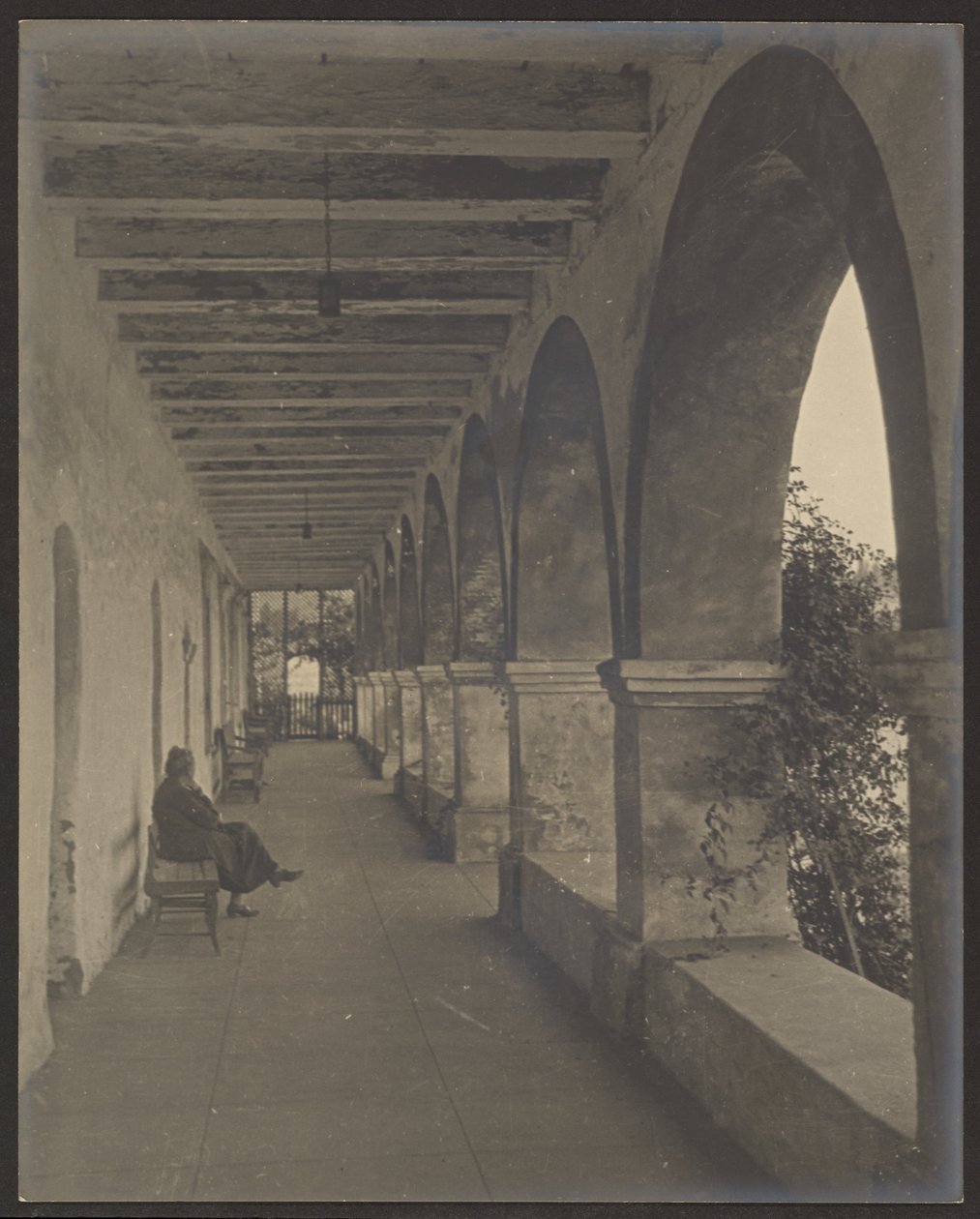 Woman Sitting in Mission Hallway by Louis Fleckenstein