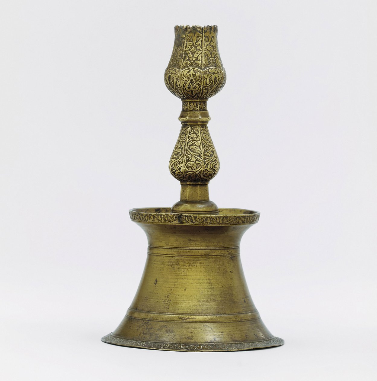An Ottoman brass candlestick, the neck with incised arabesque decoration rising into the shape of a tulip by Ottoman School