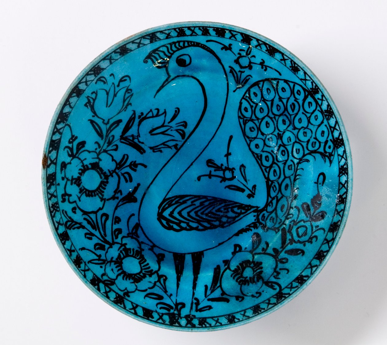 A 19th century Persian pottery dish depicting a peacock on a turquoise background by Persian School