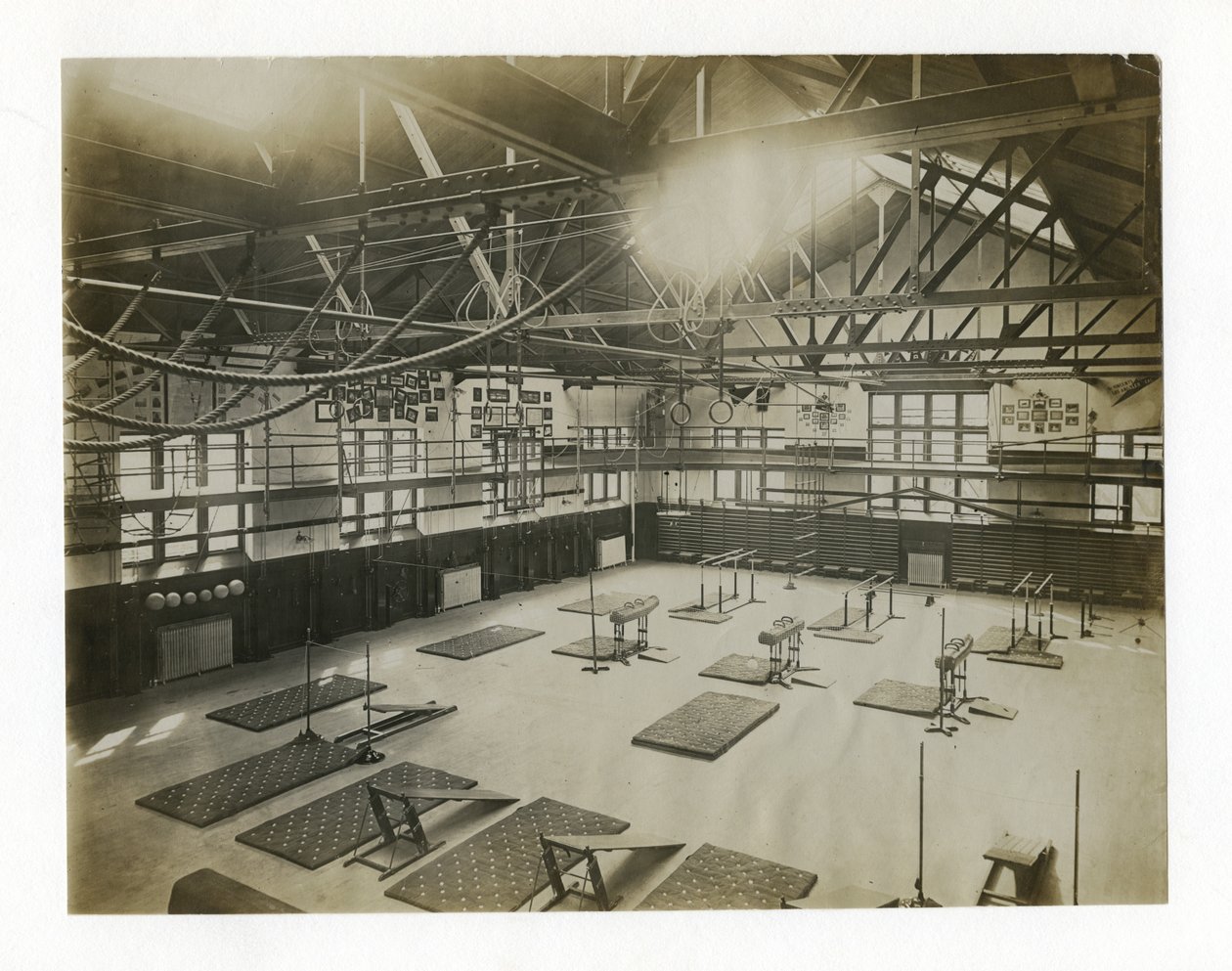 Horizontal Photograph of the Interior of a Large Gym. Equipment and Mats are Spread Out on the Floor by Unbekannt