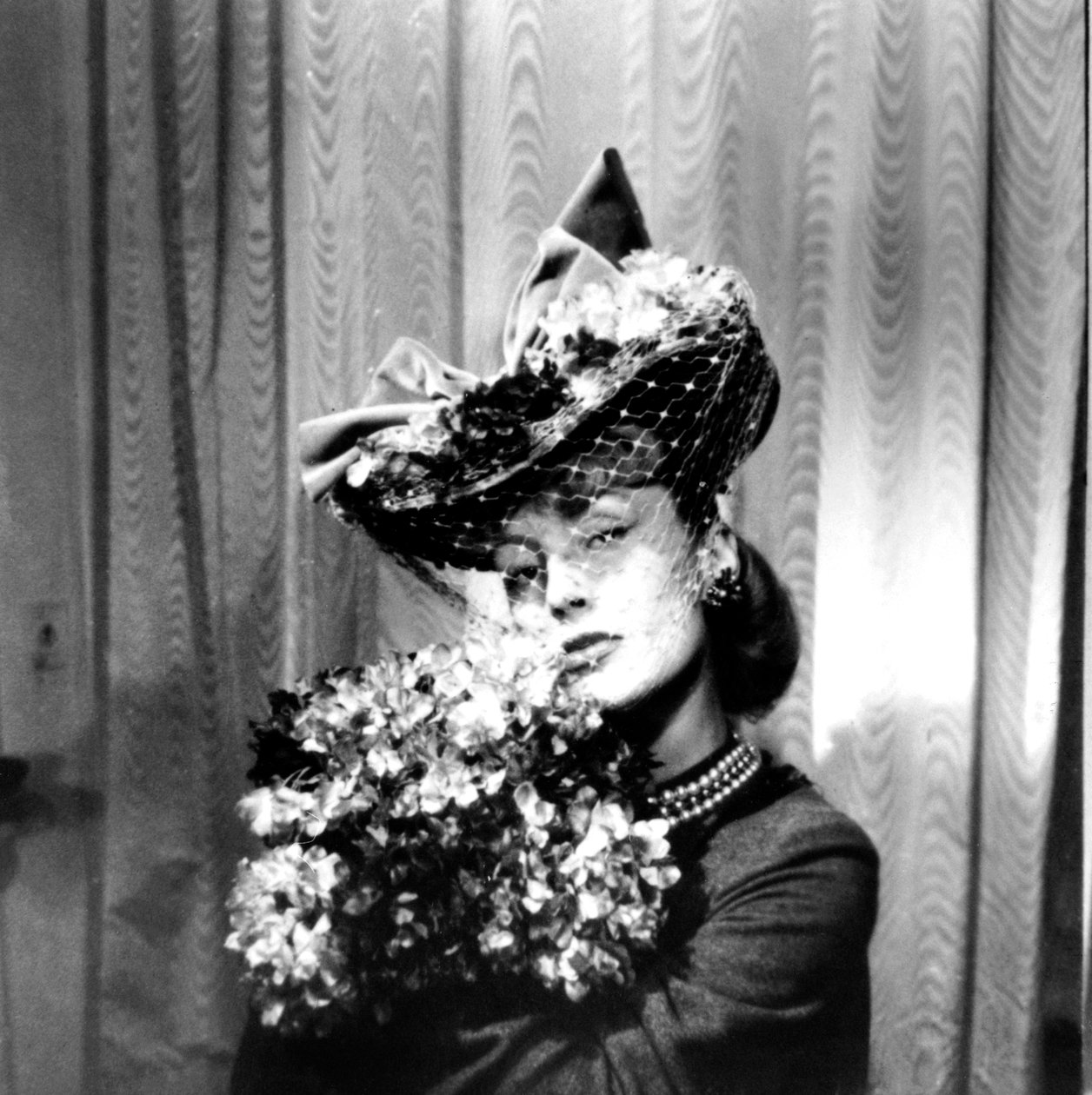 Woman wearing a hat with a veil, holding a bouquet of flowers, Paris by Unbekannt