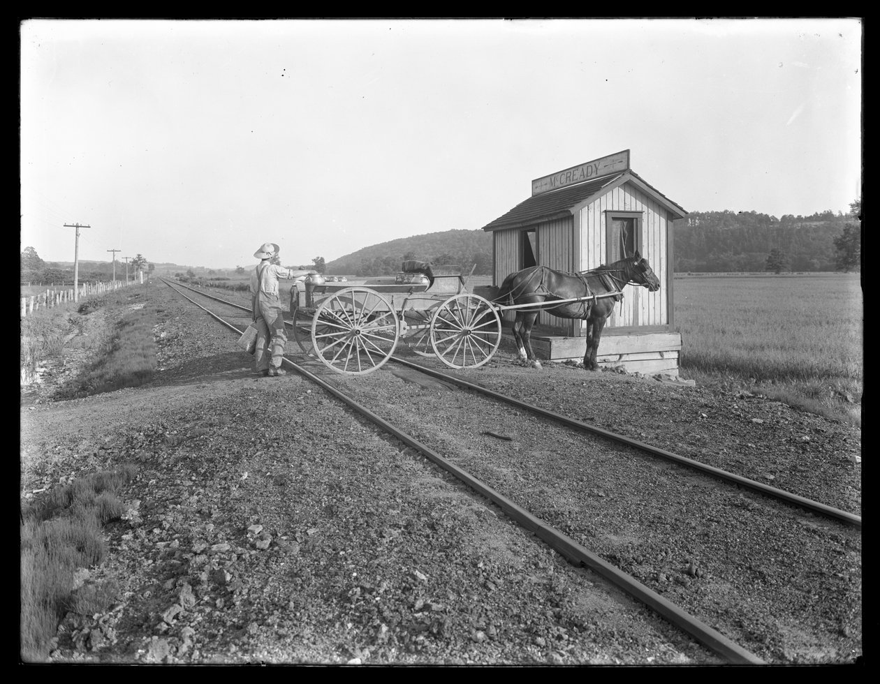 Unidentified man loading milk on to horse-drawn cart parked over railroad tracks outside the McCready farm, Pennsylvania, c.1913 by William Davis Hassler