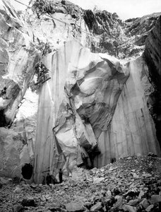 Excavators at work along a steep wall of a marble quarry in the Apuan Alps, Tuscany