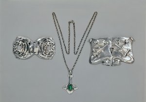 Silver jewellery designed for Liberty. Left to right: Waist clasp with interlaced Celtic design, 1904. Pendant and chain set with cabochon-cut chrysoprase. Waist clasp with repousse design on hammered by Archibald Knox