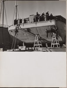 A group of men work on a docked boat