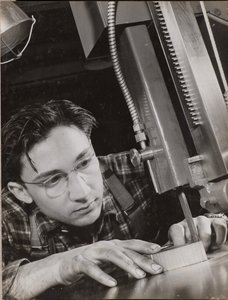 Man wearing glasses working with an industrial file by Arnold Eagle
