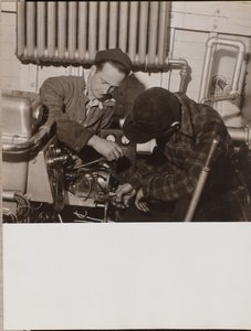 Two Men Work on a Machine Using a Screwdriver and a Wrench
