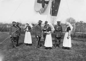 A group of unidentified officers, nurses and men of the 3rd Australian Casualty Clearing Station gathered beneath a flag pole flying the Australian flag and the Red Cross flag
