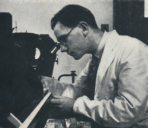 Research worker with microscope testing the structure of an aluminium alloy, 1941