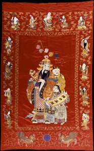 A Chinese Embroidered Red Satin Hanging Depicting a Figure with a Ru-i and Two Attendants, the Borders Decorated with the Eight Immortals by Chinese School