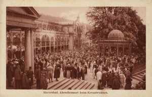 Postcard depicting a crowd of people attending an evening concert at Kreuzbrunnen by Czech Photographer