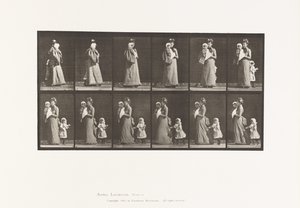 Walking carrying child, turning around; another child holding on to dress by Eadweard Muybridge