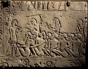A group of Negroid prisoners surrounded by guards armed with clubs while a scribe draws up a report, relief from the tomb of Horemheb at Saqqara by Egyptian 18th Dynasty