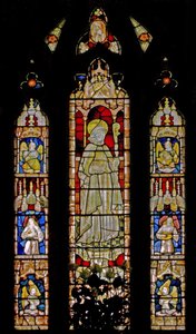 The East window depicting musician angels surrounding the central figure of a sainted bishop by English School