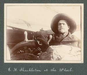 E H Shackleton standing by wheel of the 