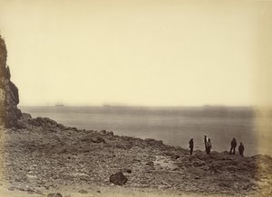 View of shore with ships on horizon and five figures standing on beach