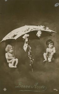 Happy New Year card with two babies hanging from an umbrella by French Photographer