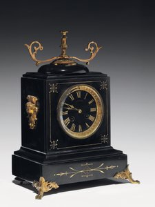 A mantle clock of black composition stone, with incised decoration, with legs, finials and fittings in gilt brass, by Jausions of Pau, France, c.1876-78 by French School
