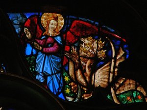 The west rose window depicting a scene from the Book of Revelation: Dragon persecutes the mother of the man child; but she has wings with which to fly into the wilderness by French School