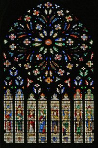 Window w237, the west rose window, depicting the Lamb of the Apocalypse at the center surrounded by 12 angel musicians; coats of arms that include Montmorency-Laval, Bertrand Duguesclin and Oli by French School