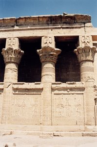 The south wall of the Roman Birth House, or Mammisi, with reliefs depicting a pharaoh making offerings to gods and columns topped with images of Bes