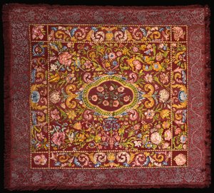 An Italian table carpet embroidered in brightly coloured silks with a central medallion of roses within a field of lilies and larger flowers by Italian School