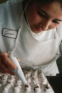 A Godiva chef attaches chocolate stems to fondant-covered cherries, Brussels, Belgium
