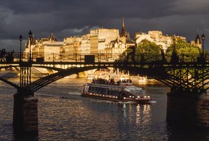 Dark clouds are overhead as a boat passes under the Pont des Arts. Seine River, Paris