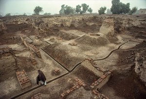Overview of a pit filled with the remains of brick walls and a brick well