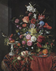 Flowers in a glass vase on a draped table, with a silver tazza, fruit, insects and birds