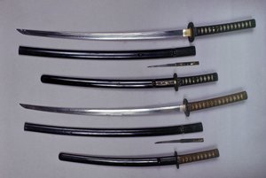 Top: a katana, Japanese sword and its sheath, wakizashi, Japanese short sword in its sheath, small Kokatawa dagger stows in the same scabbard. All three are from the 18th century. The lower ones are from the 17th century