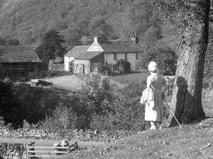 A woman stands next to a tree with her back to the camera looking out towards Yew Tree Farm