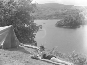 View of young woman wearing a swimming costume and lying on a lilo, lake in background
