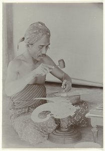 Javanese Man Creating a Human-Like Figure with Hammer and Instruments by Kassian Cephas