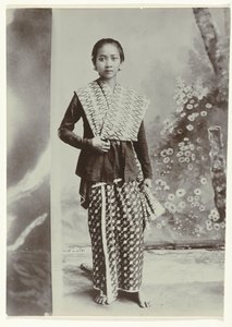 Studio portrait of a young Javanese woman in a sarong with batik motif and a checkered shirt